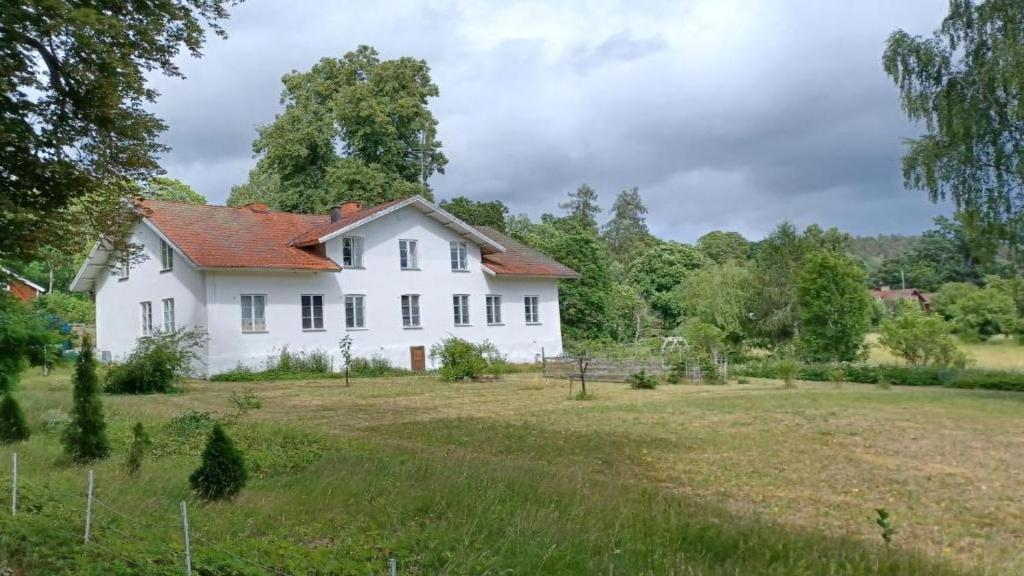 a white house in a field with a yard at Förvaltarbostaden in Åtvidaberg