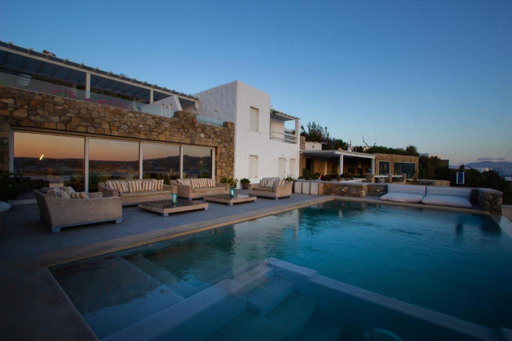 uma piscina com sofás e uma casa em Amaris Mykonian Residence em Ornos
