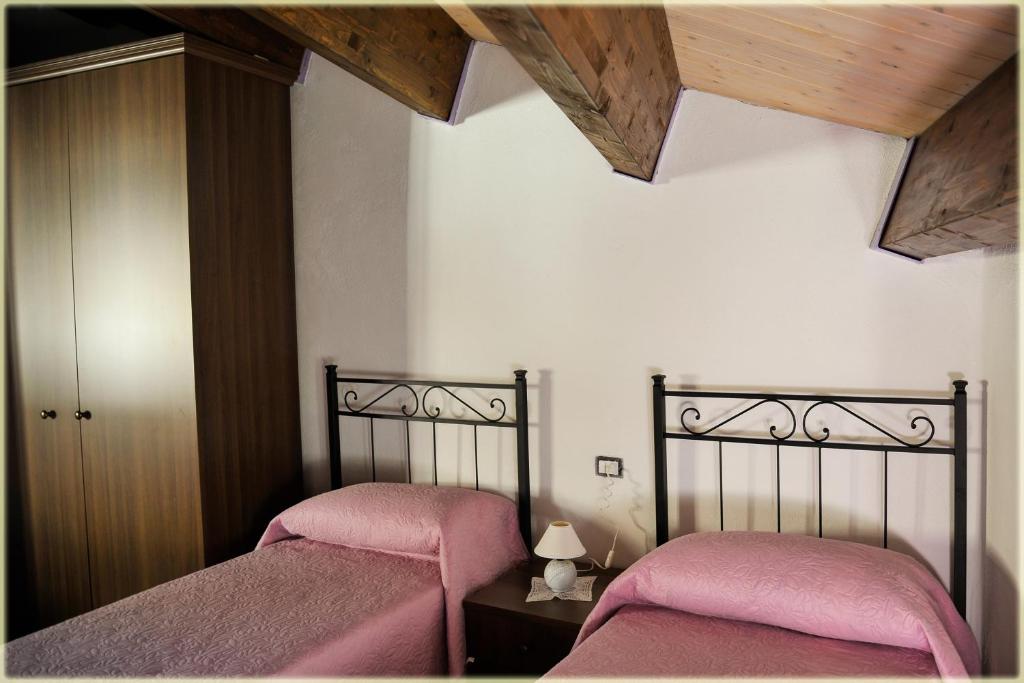 1 dormitorio con 2 camas con sábanas rosas en Il Palazzo del Barone - Stanza dei Ravelli, en Pietrapertosa