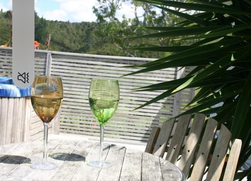 two glasses of wine sitting on a table at Dream Weavers Farm Cabin in Karetu