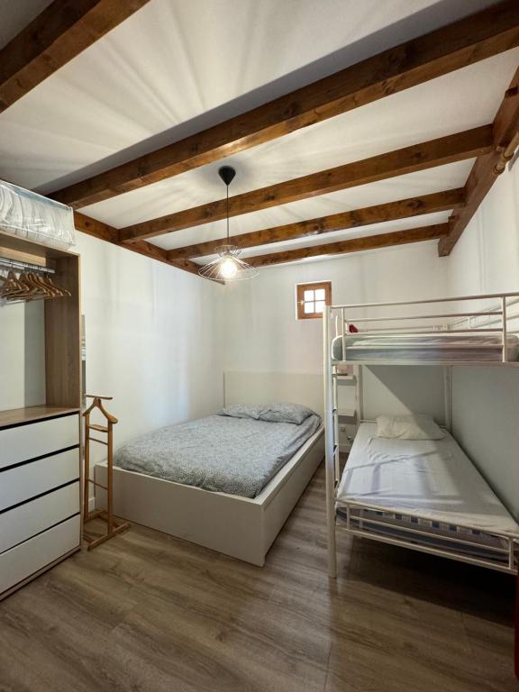 a bedroom with two bunk beds and a ceiling with beams at Maisonnette à 5mn des plages. in Guéthary