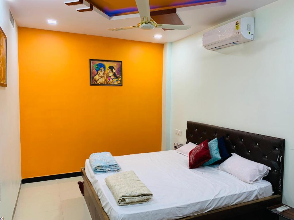 a bed in a room with an orange wall at Manjushree Guest House in Ujjain