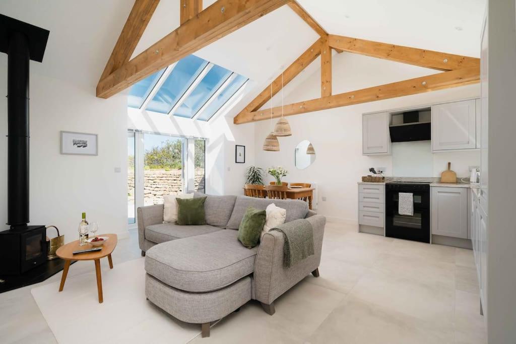 a living room with a couch and a kitchen at Meadow View Barn, Rural St Ives, Cornwall. Brand New 2 Bedroom Idyllic Contemporary Cottage With Log Burner. in Nancledra