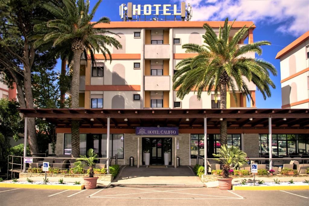 a hotel with palm trees in front of it at Hotel Califfo in Quartu SantʼElena