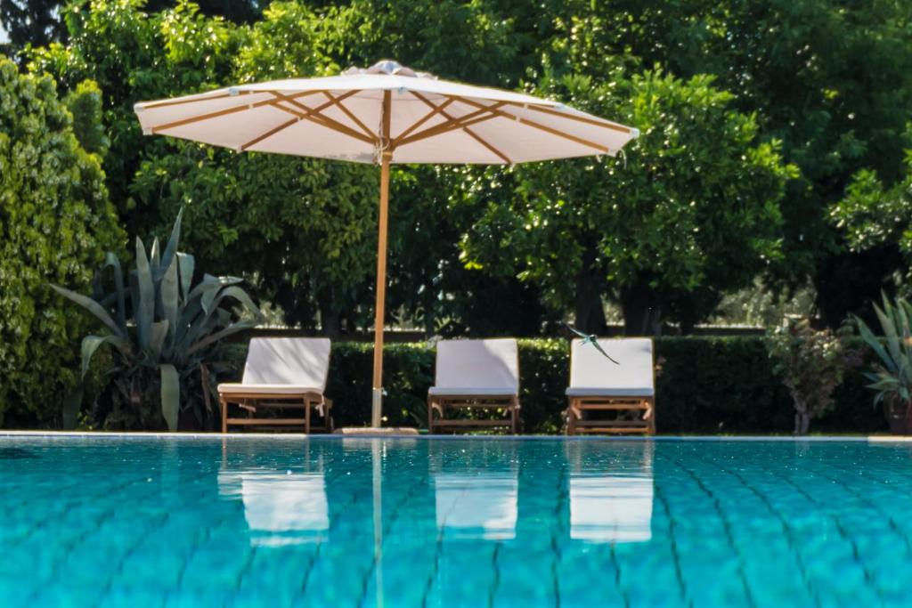 Káto Lekhónia的住宿－Pelion's Finest Estate，游泳池旁的遮阳伞和椅子