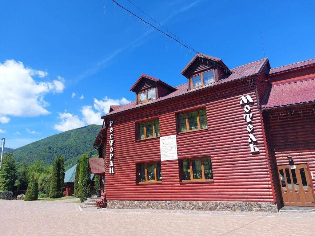 um edifício vermelho com uma montanha ao fundo em Trembita em Mizhhirʼʼya