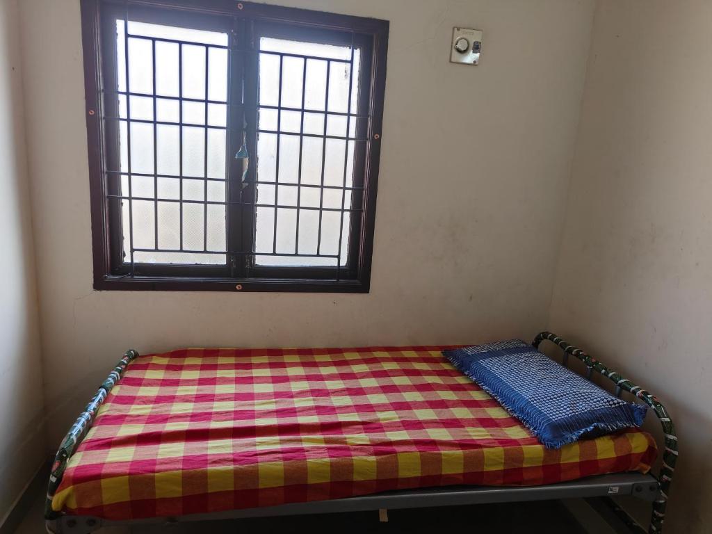 uma pequena cama num quarto com uma janela em AGP Castle em Chennai