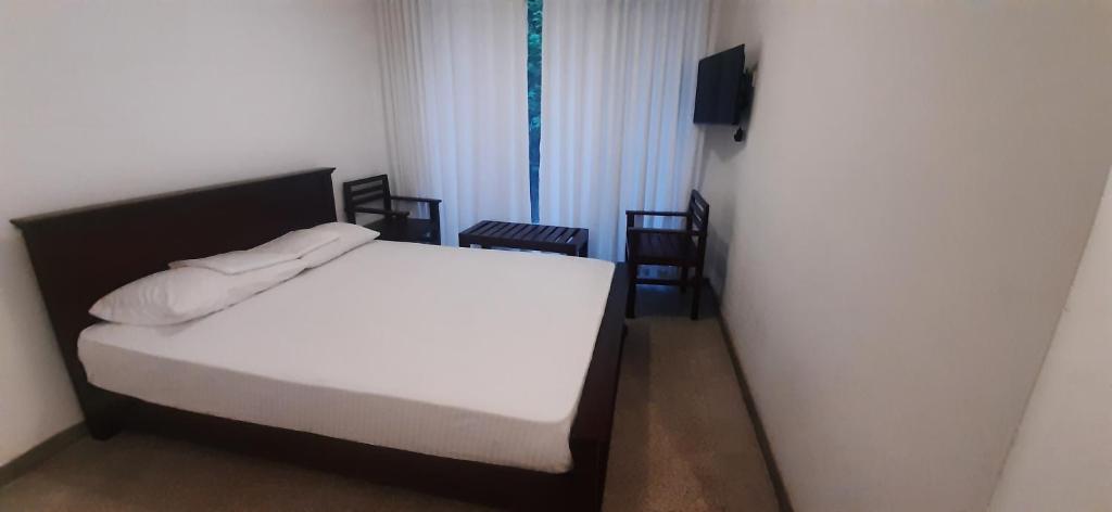 - une chambre avec un lit, des chaises et une télévision dans l'établissement Laurel Residence, à Kandy