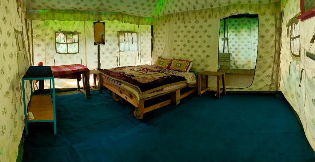 a bedroom with a bed and a table in a room at Shoolin Cottages & Camp's in Kasol
