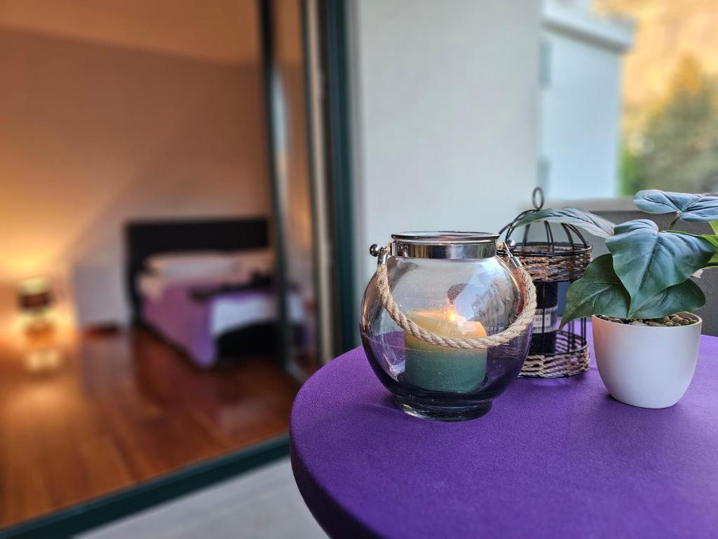 a candle in a glass vase on a purple table at Sweet suite in Makarska