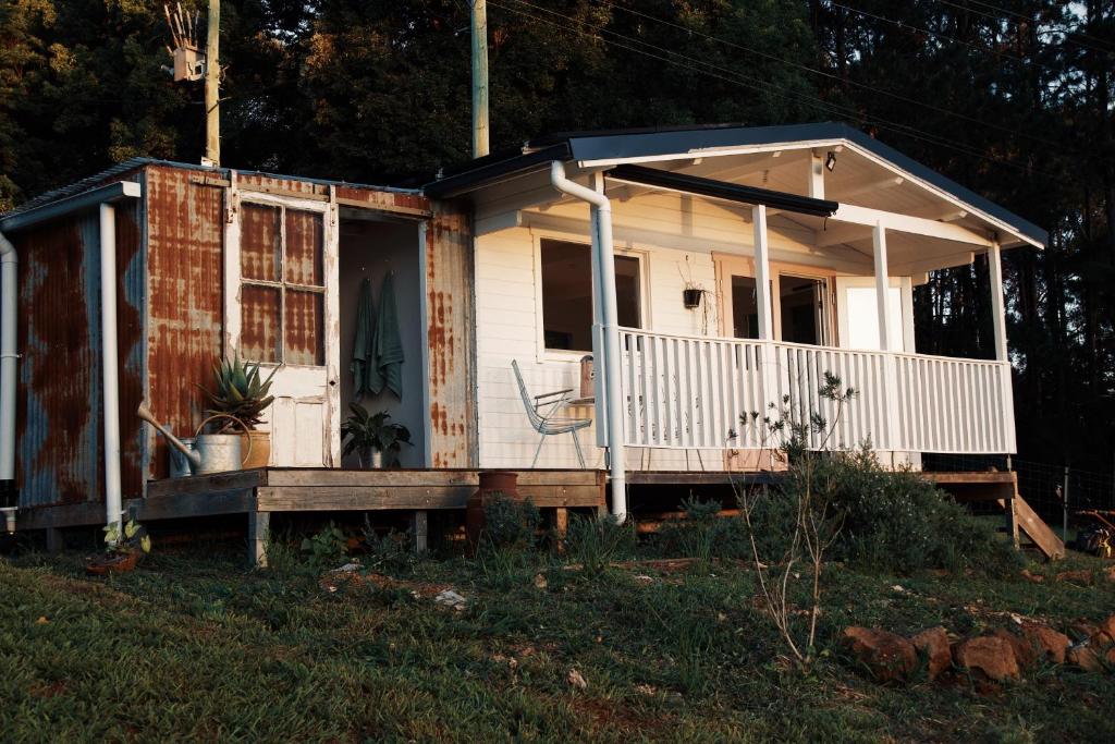 a small white house with a front porch at Byron Hinterland Rustic Off Grid Cabin in Rosebank