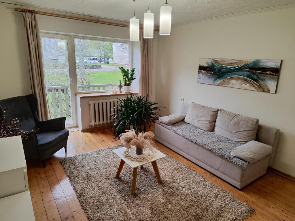 ein Wohnzimmer mit einem Sofa und einem Tisch in der Unterkunft Cozy two-room apartment in Priekuļi