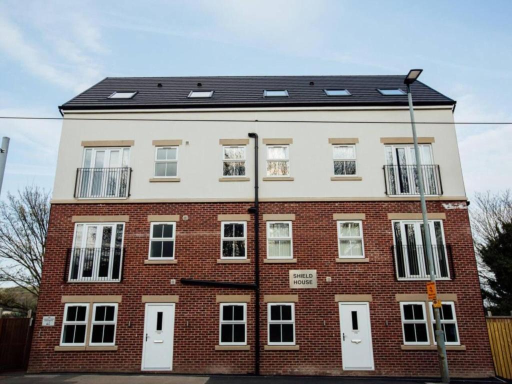 a large brick building with white doors and windows at 1 2 Bedroom Shield House Apartments Sheffield Centre in Sheffield