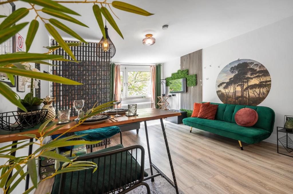 - un salon avec un canapé vert et une table dans l'établissement Urban Jungle Studio Apartment, à Offenbach-sur-le-Main