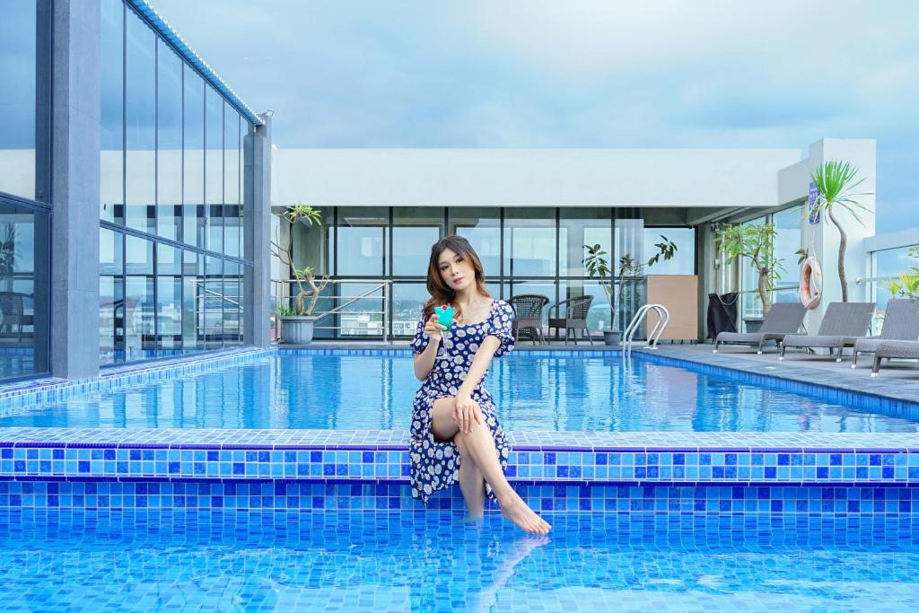 a woman in a dress sitting next to a swimming pool at Merapi Merbabu Hotels & Resorts in Yogyakarta