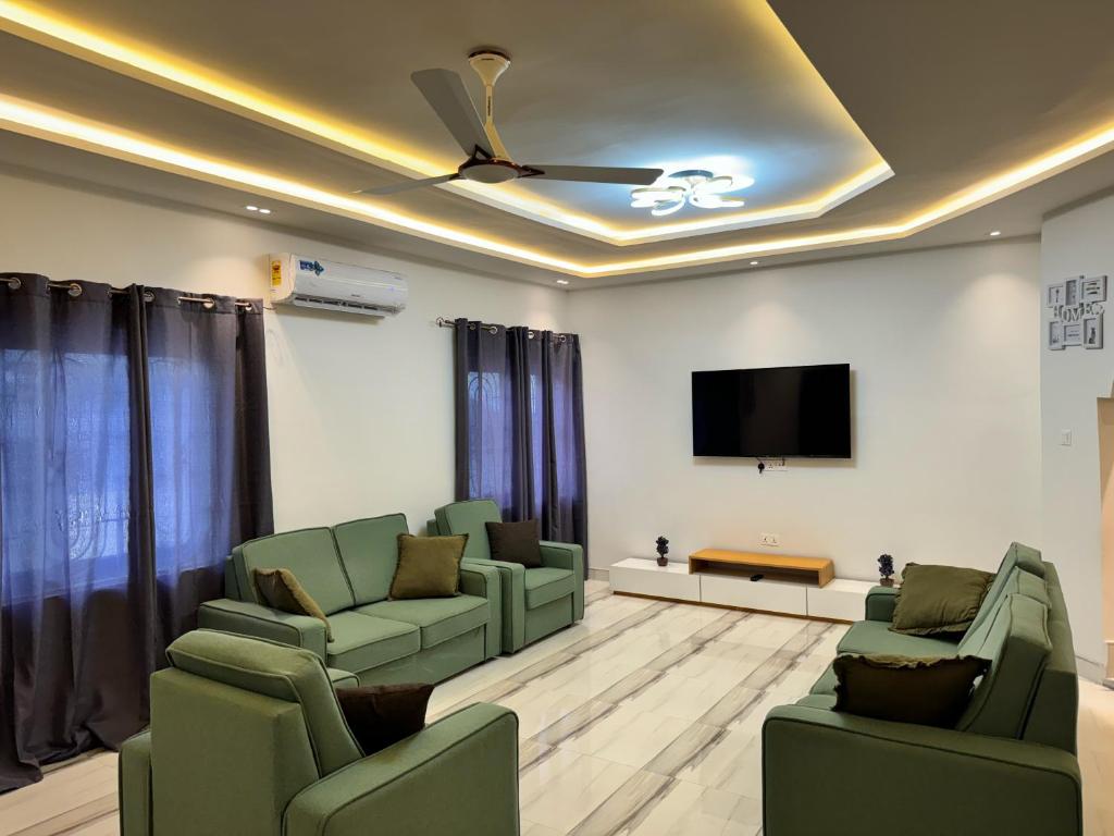 una sala de espera con sillas verdes y TV de pantalla plana en Private Apartments in a Home, en Ejisu