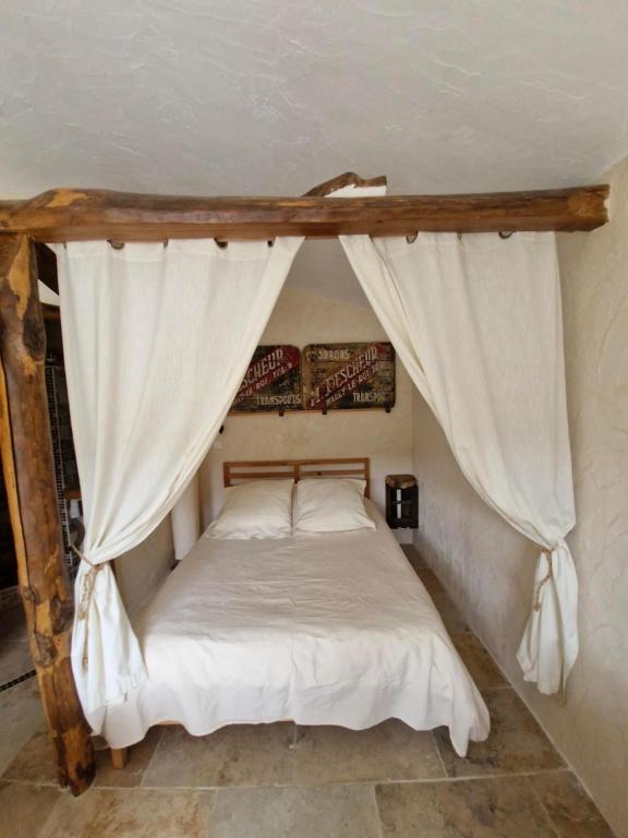 een slaapkamer met een hemelbed en witte gordijnen bij Studio au cœur du Verdon in La Palud sur Verdon