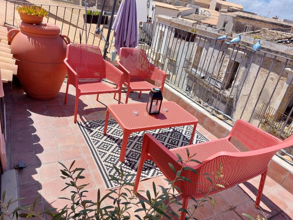 un grupo de sillas y mesas rojas en un balcón en La Colombaia Di Ortigia, en Siracusa