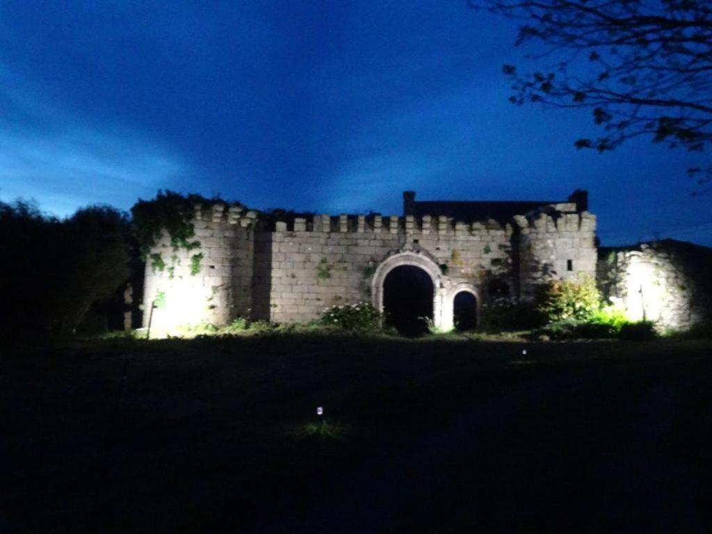un vieux château éclairé la nuit dans l'établissement Petit gîte du Manoir de Keryvoas, à Kerlouan