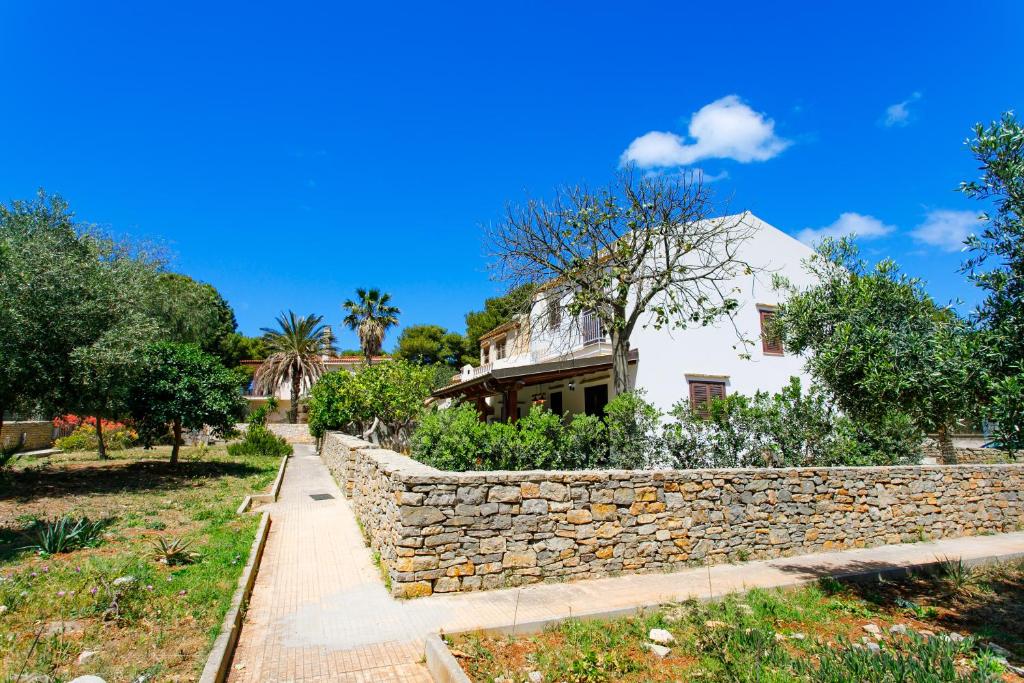 a stone wall in front of a white house at SanVitoTour- Residence Il Baglio in San Vito lo Capo