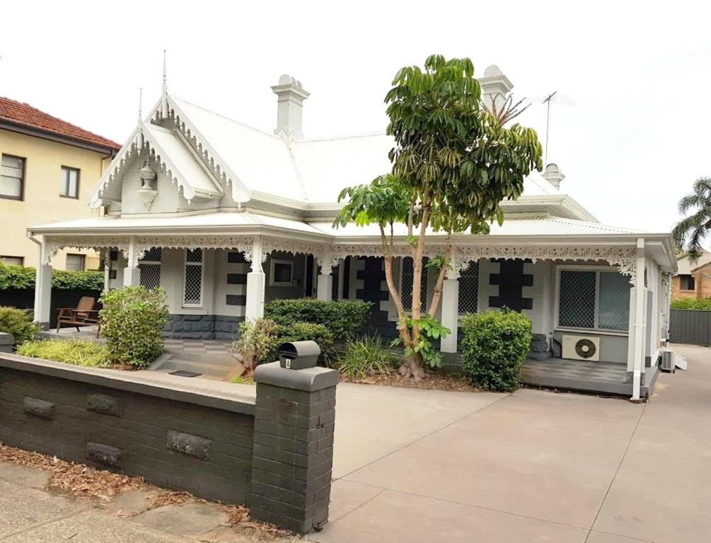 uma casa branca com uma árvore em frente em Subiaco Heritage House "gem" em Perth