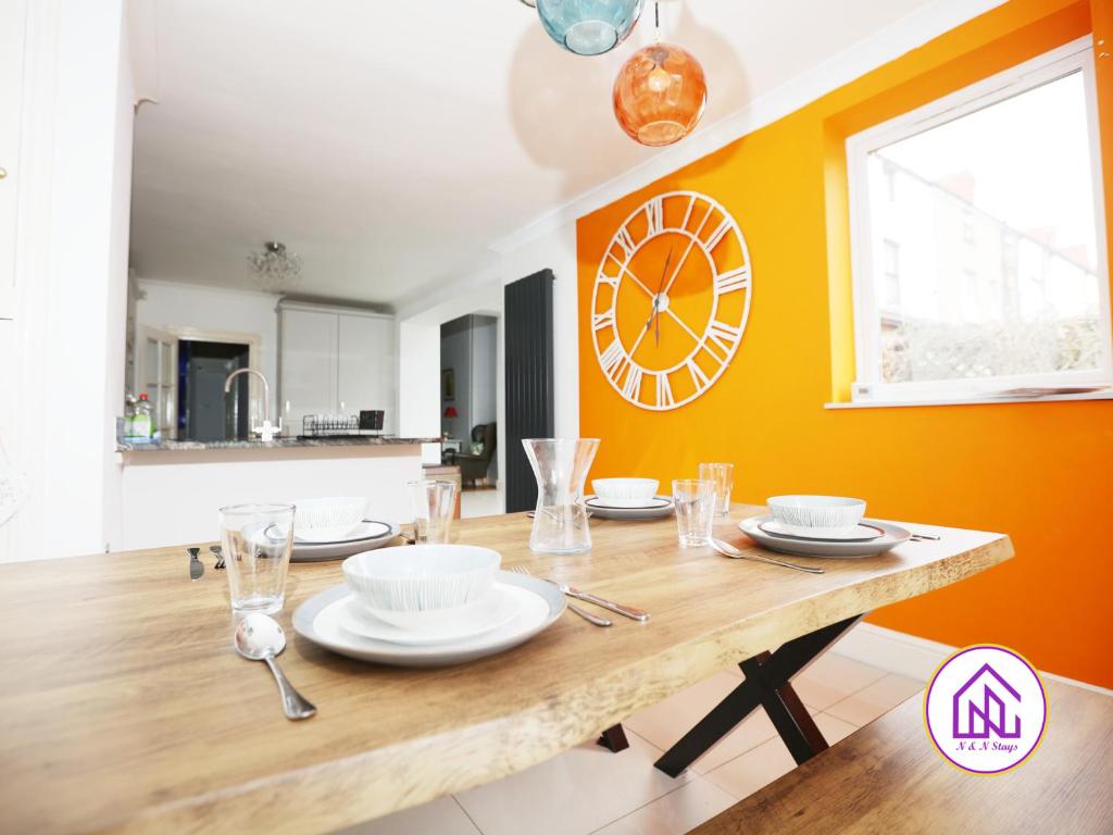 a dining room with a wooden table and a clock on the wall at Victoria House,5 Bed, Fantastic Location, Free Parking, Contractors in Cardiff