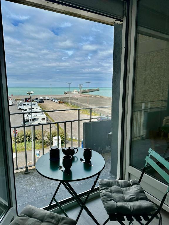 une table sur un balcon avec vue sur la plage dans l'établissement La Mer à Pied appartement vue mer, à Dieppe