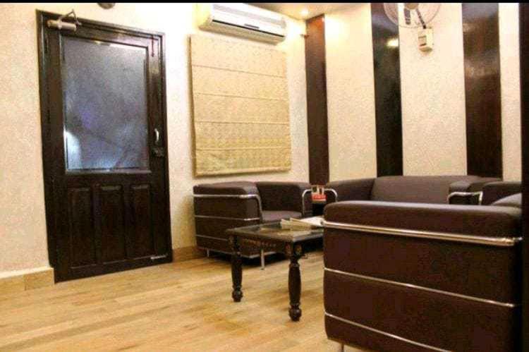 a room with a couch and a table and a door at OYO Vatika in Gurgaon