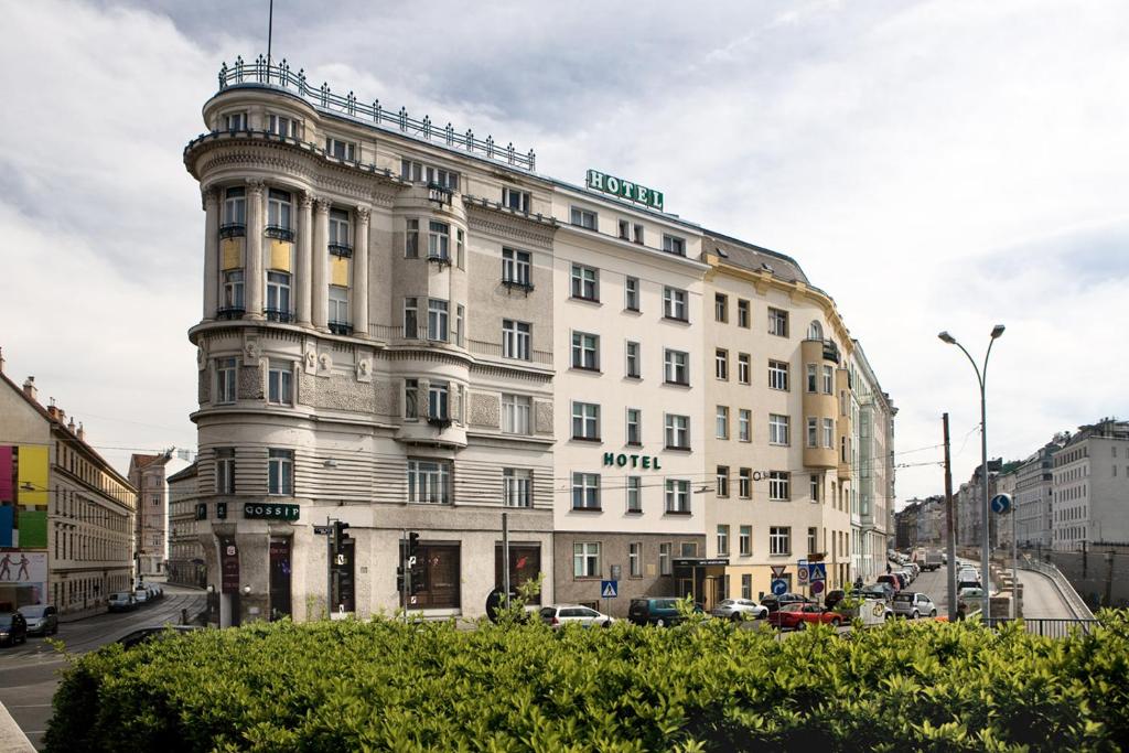 a large white building on a city street with cars at Hotel Goldene Spinne in Vienna