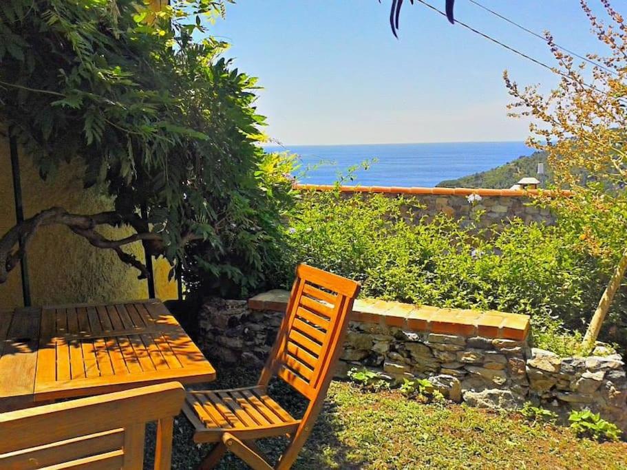a wooden table and chair sitting next to a stone wall at Casa vacanze Dolce Glicine in Bonassola