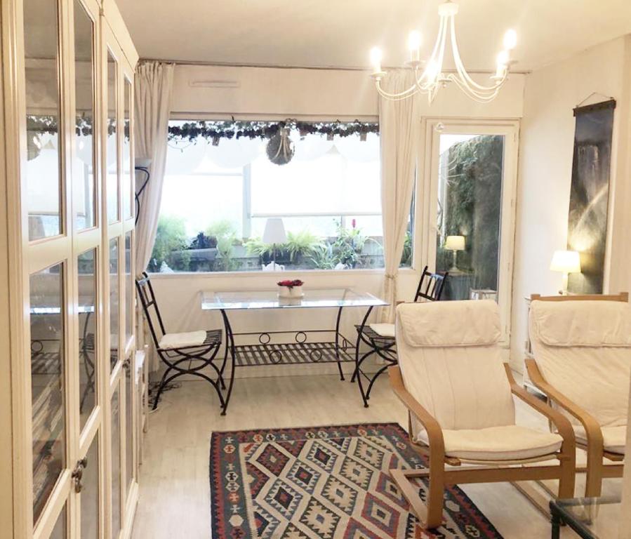 una sala da pranzo con tavolo, sedie e finestra di Appartement verdoyant a Noisy-le-Grand