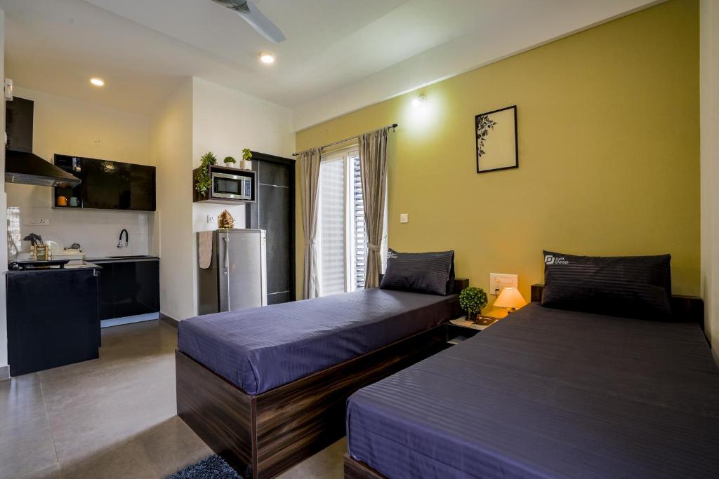 um quarto com 2 camas e uma cozinha com um frigorífico em Wandr Salm Near Rameshwaram Cafe Indiranagar em Bangalore