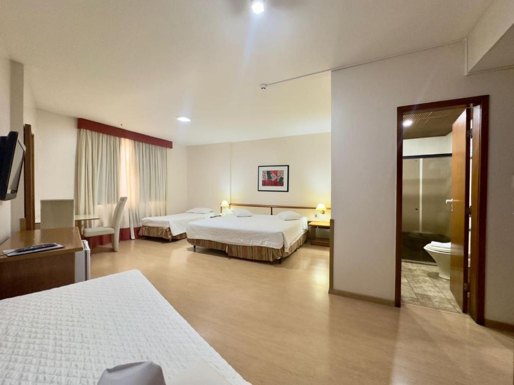 a hotel room with two beds and a bathroom at César Park Hotel in Juiz de Fora