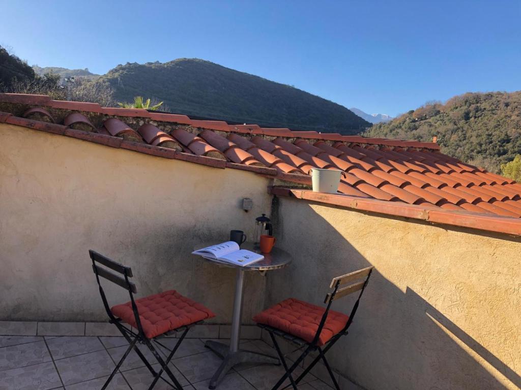 un patio avec deux chaises et une table sur le toit dans l'établissement Appartment Reynes rando, nature & relaxation !, à Reynès