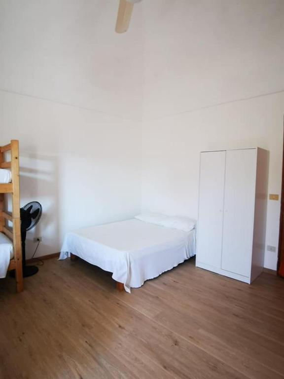 a white bedroom with a bed and a cabinet at Monolocale Ventotene in Ventotene