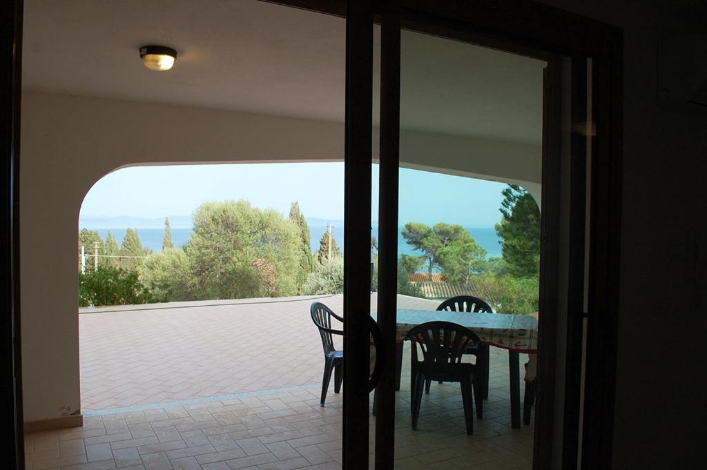 een eettafel met stoelen en uitzicht op een patio bij Nuovissimo appartamento a due passi dalla spiaggia di Maladroxia C61 in Maladroscia