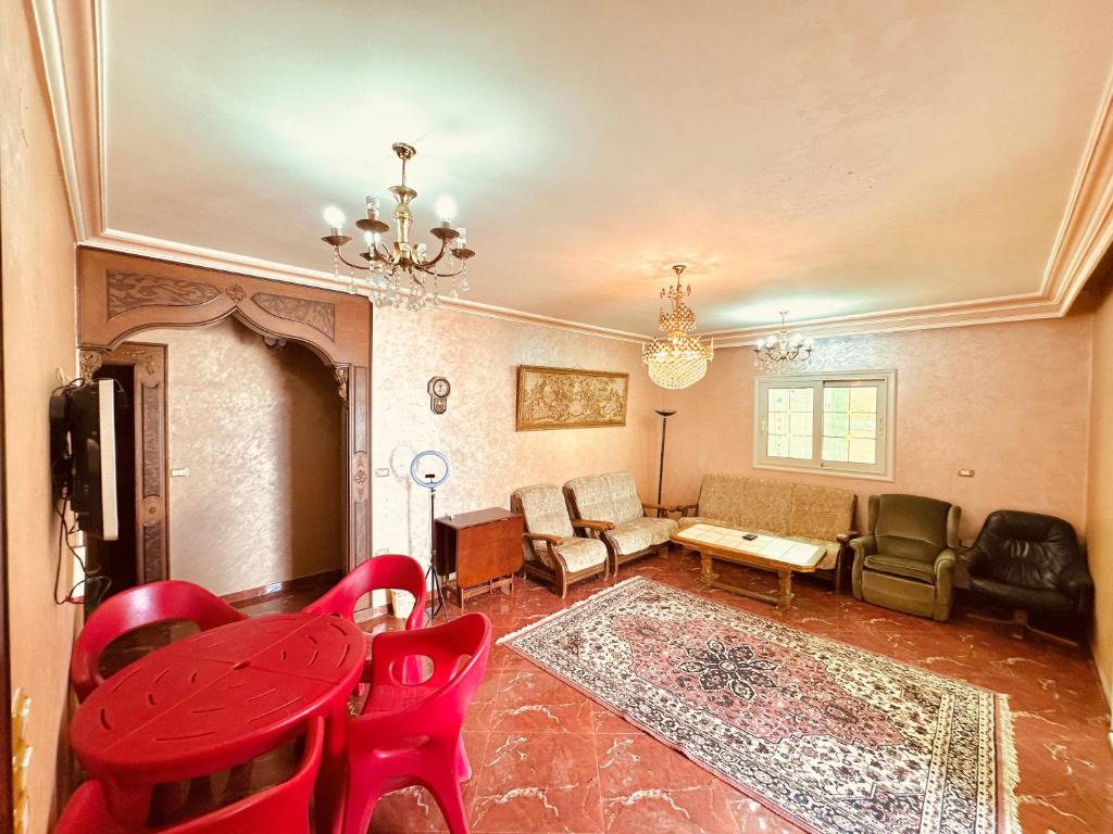 een woonkamer met een rode tafel en stoelen bij Luxury 5 star apartment with rooftop, security in Maḩallat al Burj