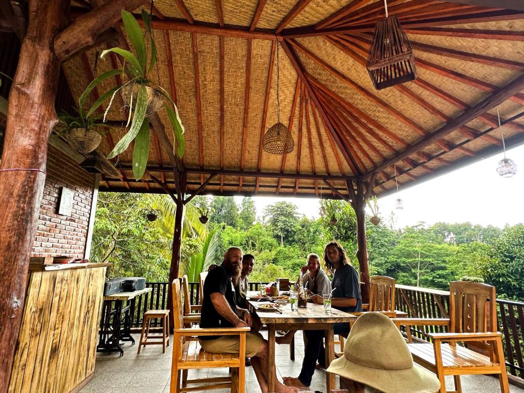 eine Gruppe von Menschen, die an einem Tisch auf einer Terrasse sitzen in der Unterkunft Artomoro Bali in Munduk