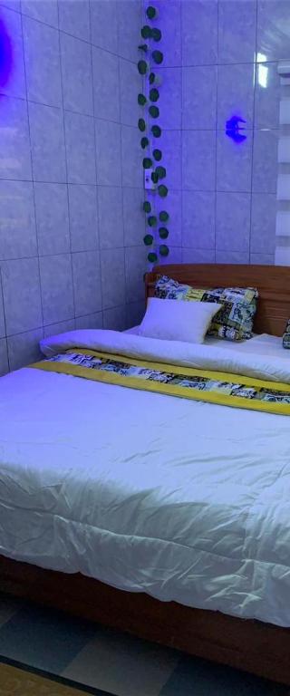 Bett mit weißer Bettwäsche und Kissen in einem Zimmer in der Unterkunft Good Vibes in Cotonou