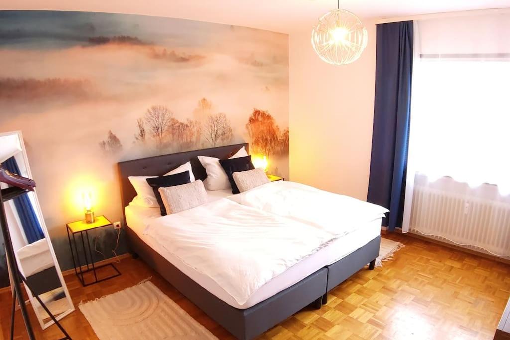 a bedroom with a bed with a painting on the wall at Bright, Modern and Spacious - Apartment "Lola" Family & Workplace in Gießen