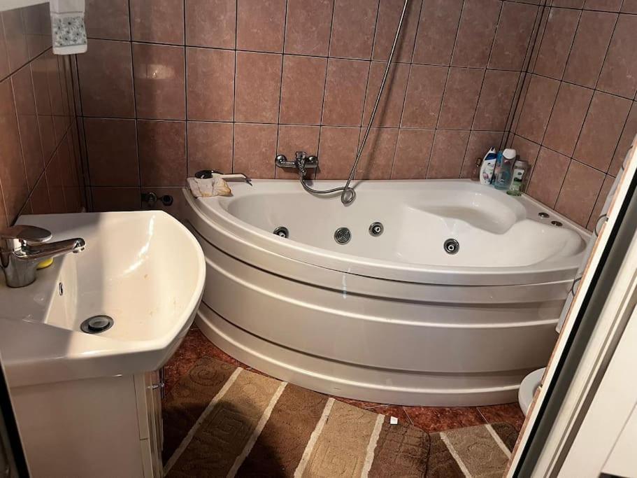 uma casa de banho com uma banheira branca e um lavatório. em Central Apartment - Book Now em Cluj-Napoca