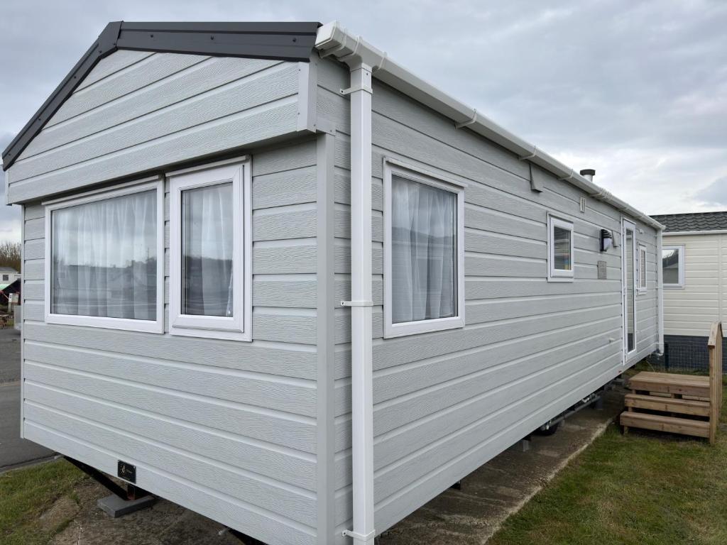 a grey tiny house with windows on a yard at Camping Oasis Middelkerke 2-slpk caravan 'New Tropical' in Ostend