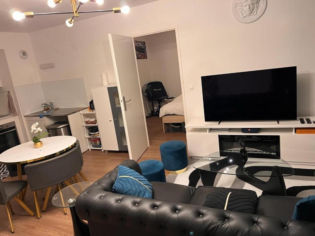 a living room with a black leather couch and a flat screen tv at appartement de luxe in Suresnes