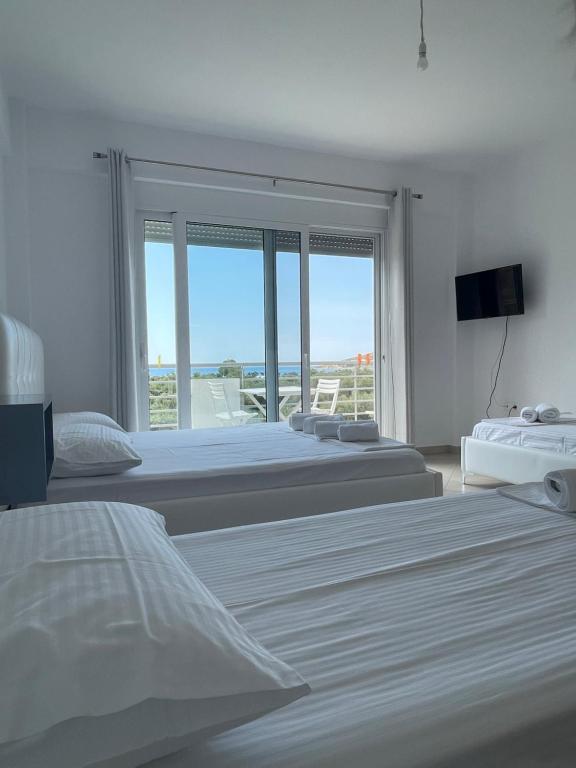 a bedroom with three beds and a large window at Qeparo Andrea Markou rooms in Qeparo