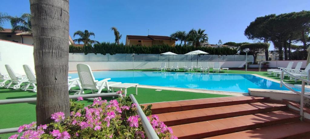 a swimming pool with white chairs and a bunch ofitures at Hotel B&B Marina in Paestum