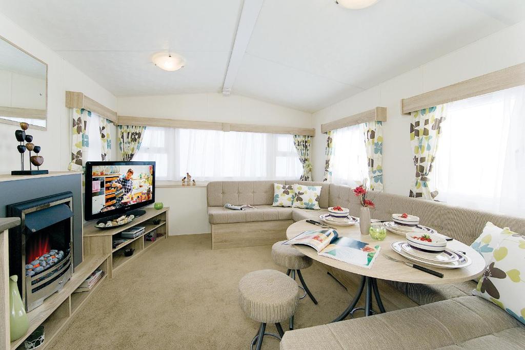 a living room with a table and a television at Marine Holiday Park in Rhyl