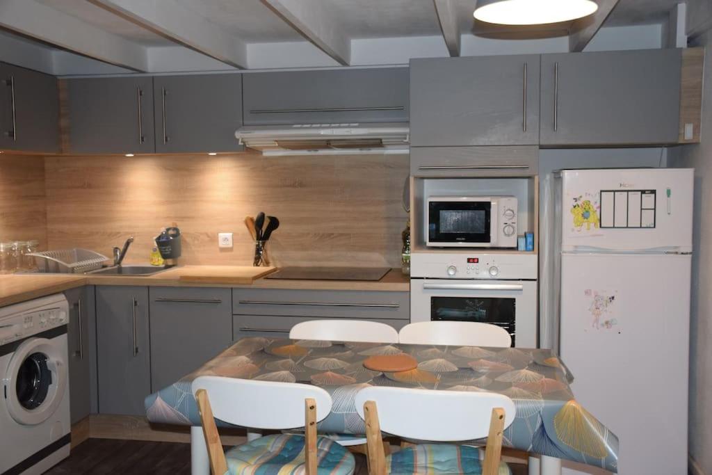 une cuisine avec une table et des chaises dans une cuisine dans l'établissement Les maisons de L'Océan, aux Mathes