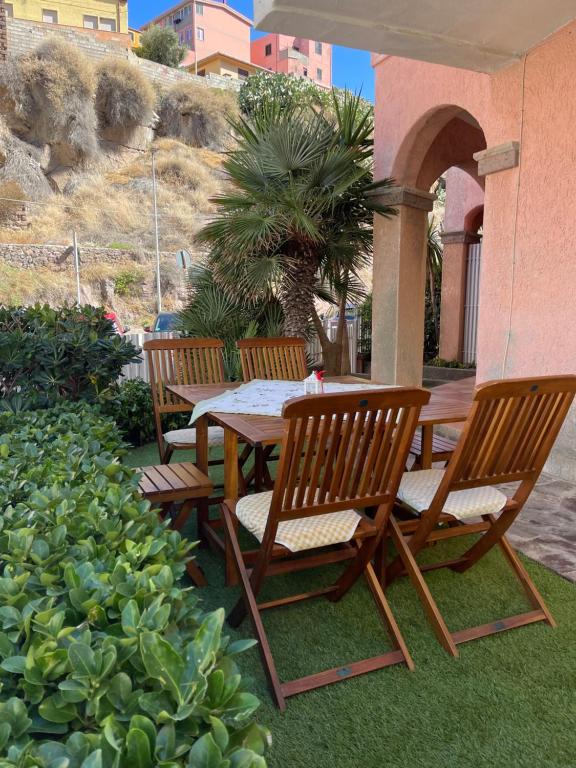 três cadeiras de madeira e uma mesa e uma palmeira em Casa Castelsardo con giardino em Castelsardo