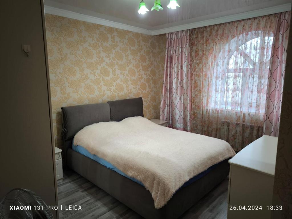 a bedroom with a bed and a window at Уютная квартира комфорт класса74 in Astana