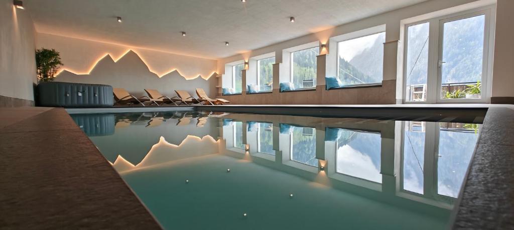 a swimming pool in a house with chairs and windows at Schlossberg in San Leonardo in Passiria